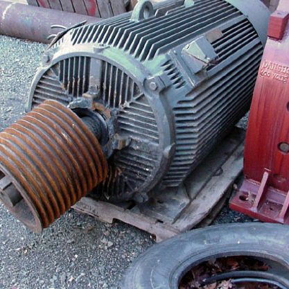 failed industrial electric motor sitting on asphalt